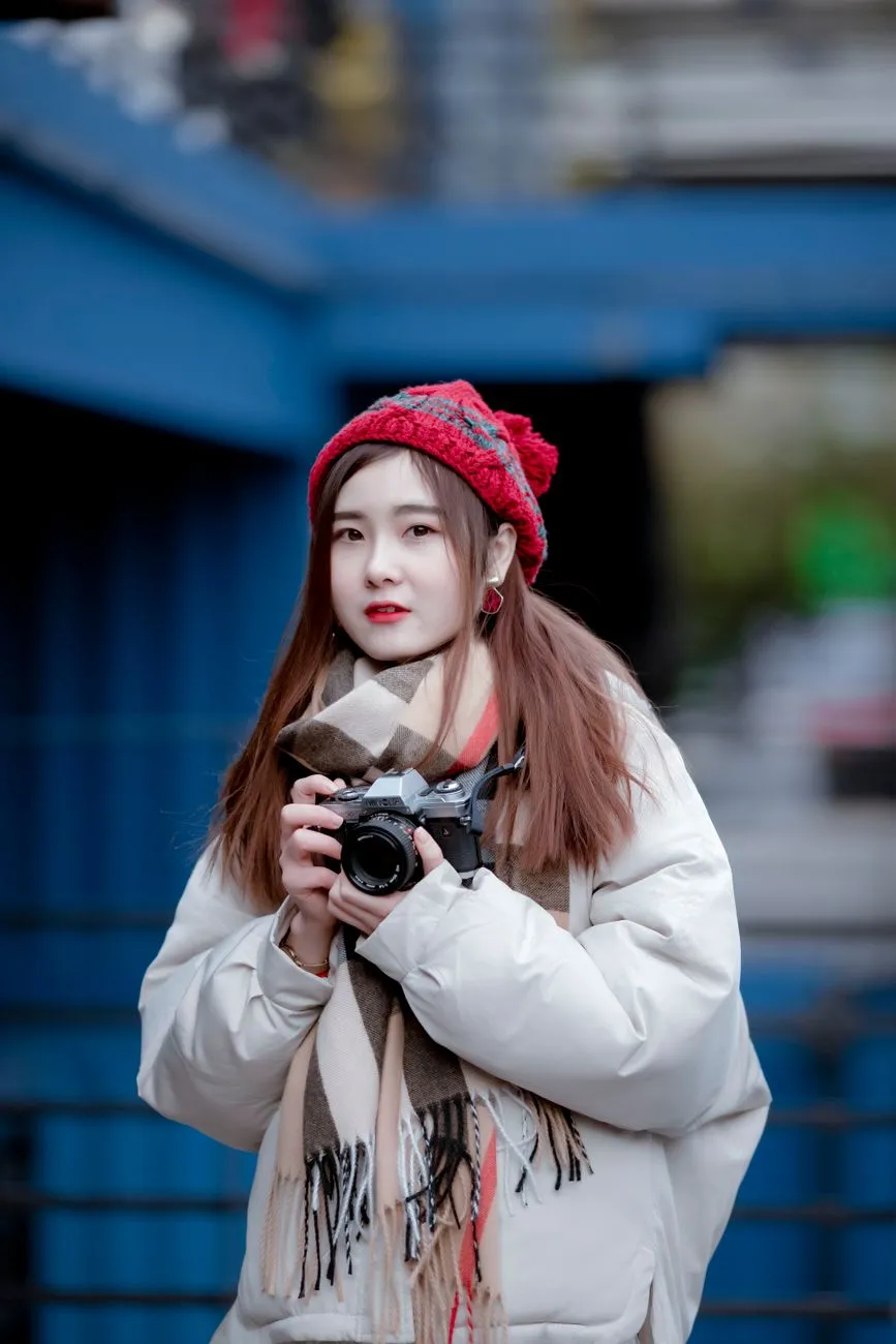 Young woman in a cream puffer jacket, knitted scarf and red beanie