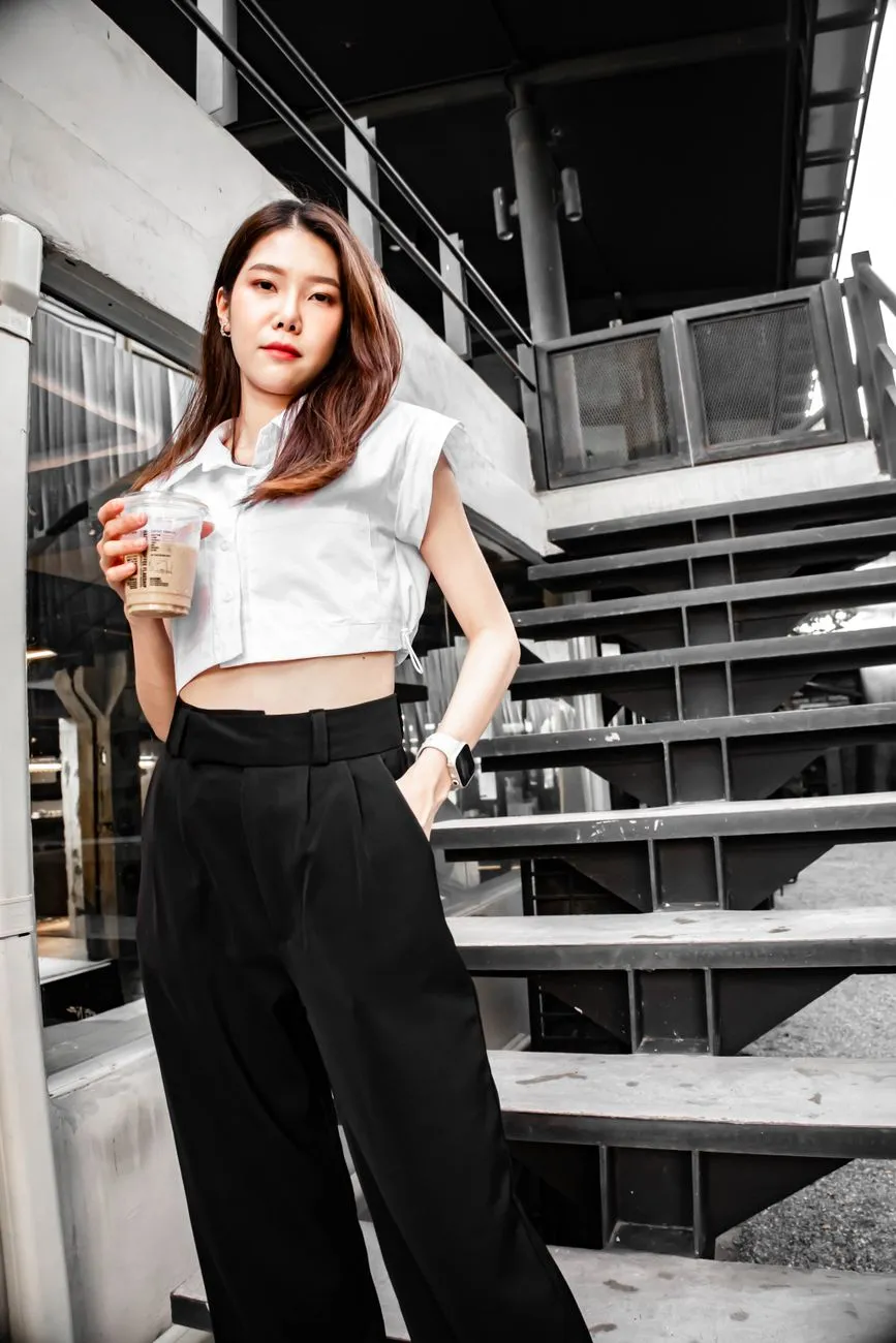 Woman in a white cropped top and high-waisted black wide-leg trousers