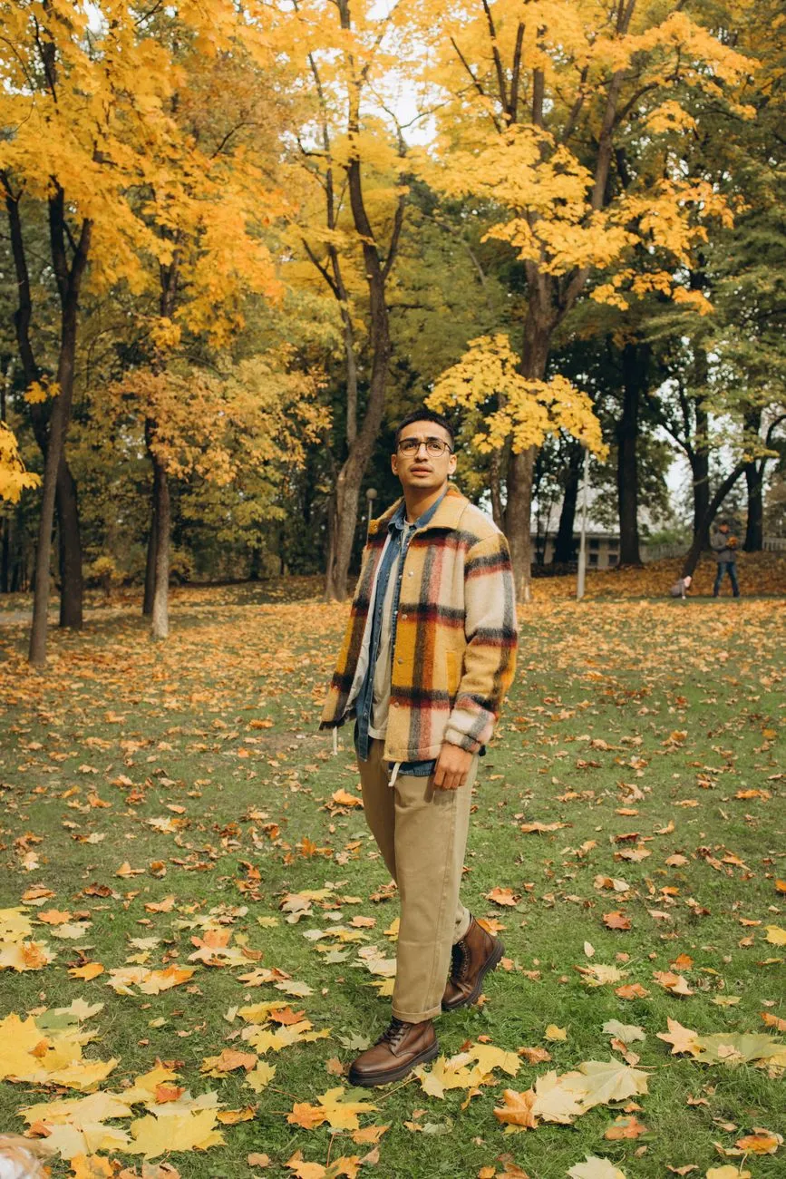 Man in an open checked jacket over a sweater with chinos in an autumn park