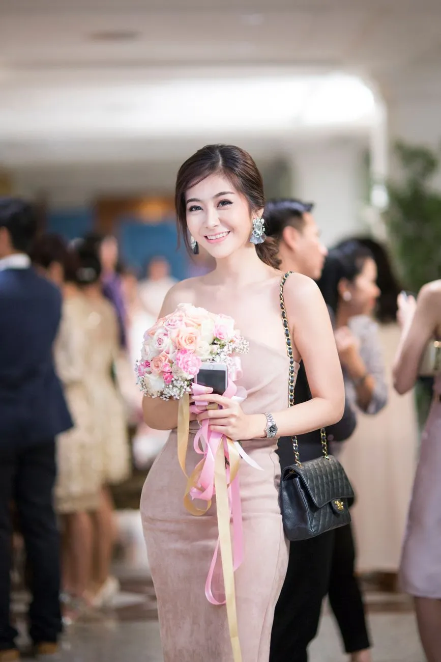 Woman in a pale pink fitted dress holding flowers at a wedding reception